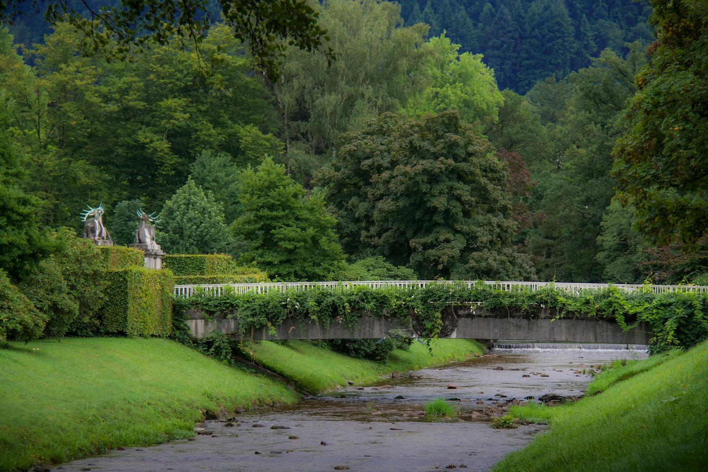 River Oos with a balustraded bridge in a green park in Baden-Baden