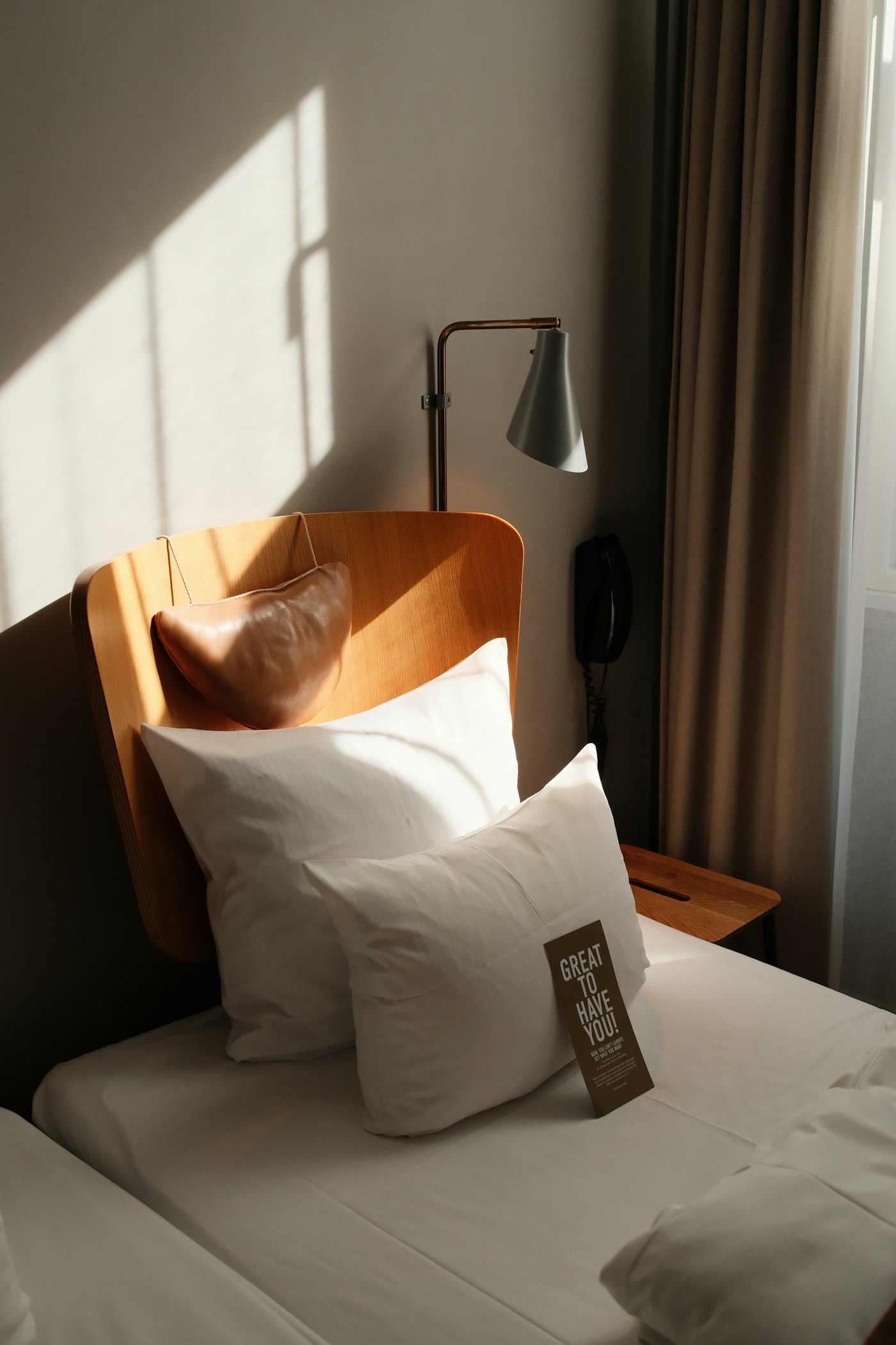 Hotel bed with white pillows and reading lamp