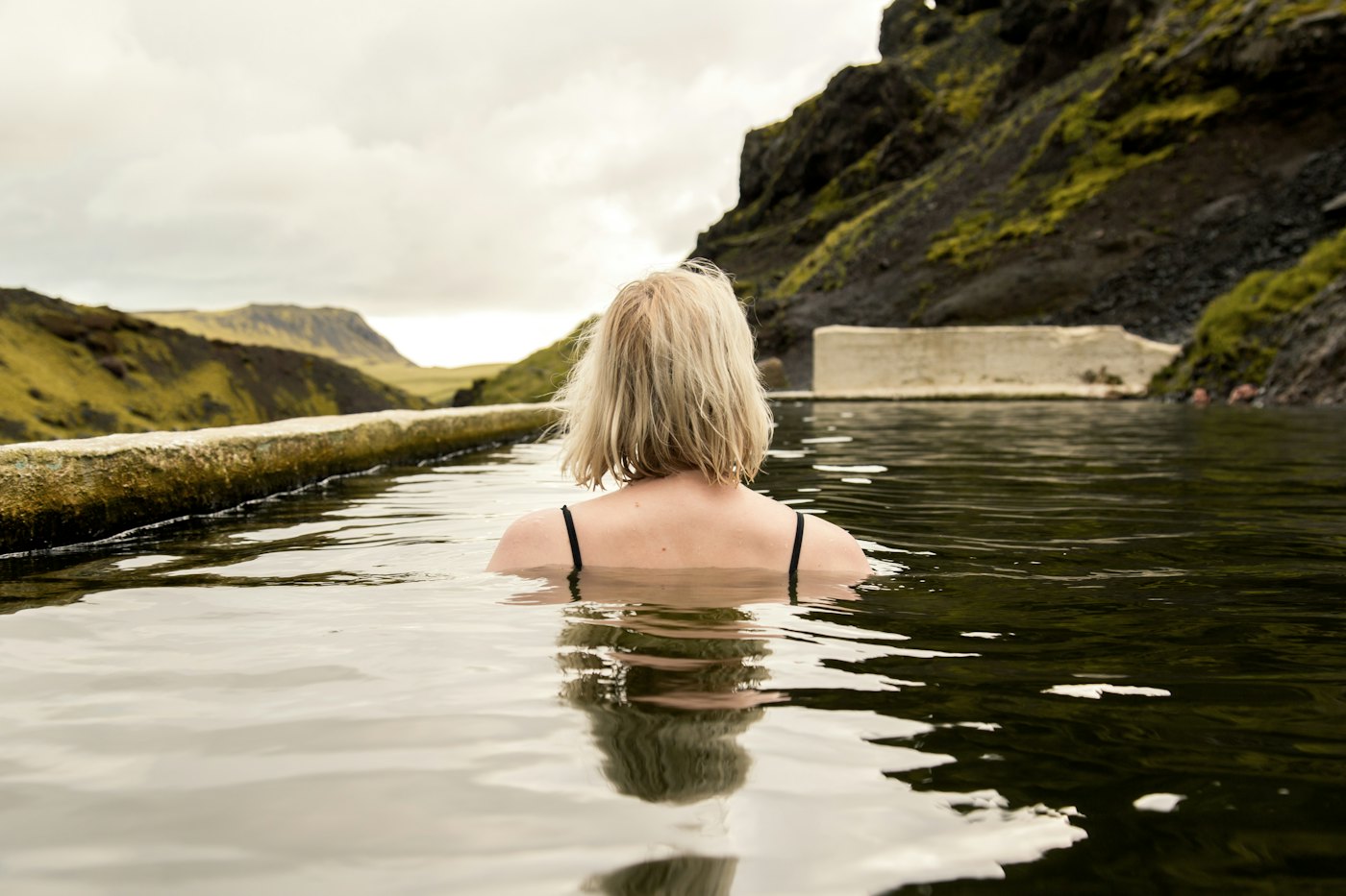 Woman alone in an outdoor pool, seen from behind